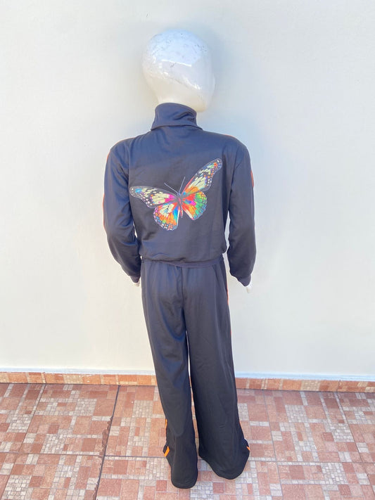 Chaqueta negra, con estampado de mariposa en la parte de atrás y líneas en color naranja en los lados.