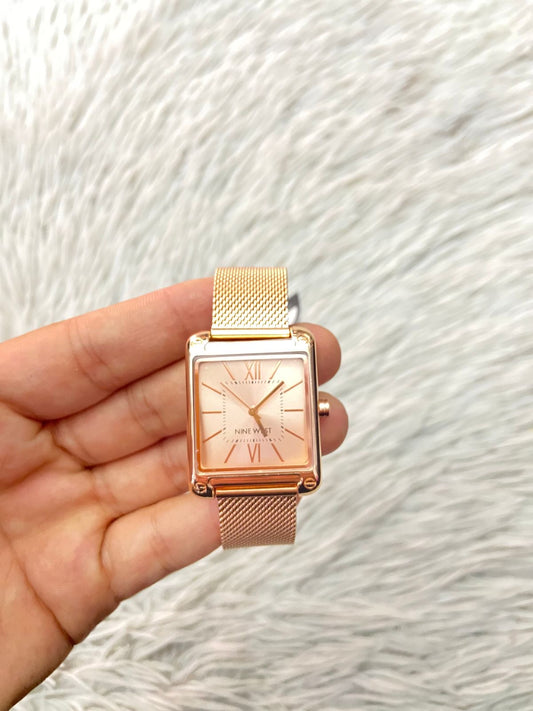 Reloj NINE WEST Original, en color rose golden/ dorado rosado con caja cuadrada, correa metalica y nombre de la marca en el fondo.