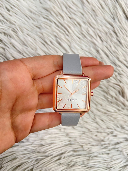 Reloj NINE WEST Original, con correa gris claro, caja cuadrada y indice y manillas en color rose golden.