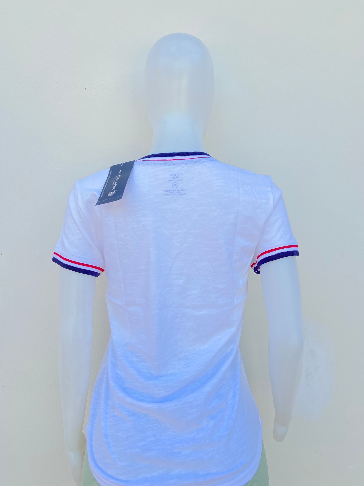 T-shirt U.S POLO ASSN. original blanco con cuello V, logotipo de la marca al frente y banda en color azul marino, blanco y rojo en cuello y mangas.