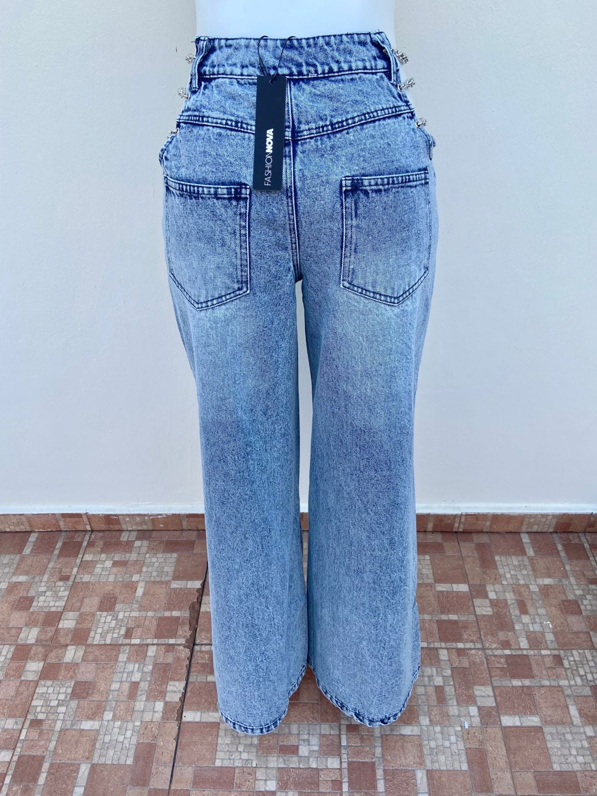 Pantalon jean ancho con degradado blanco y detalle de cadenas en los lados en color pletadas.