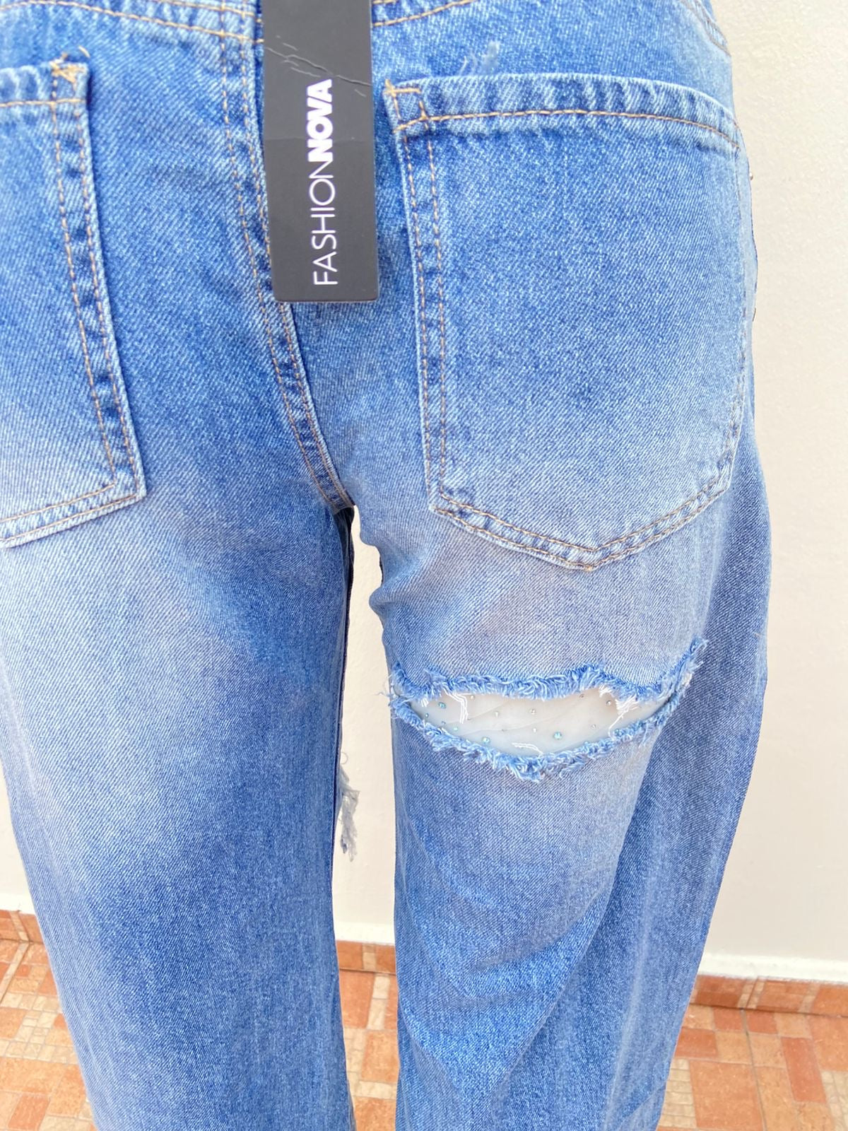 Pantalón Jean, azul con varios rasgados y malla transparente con brillos en los rotos.