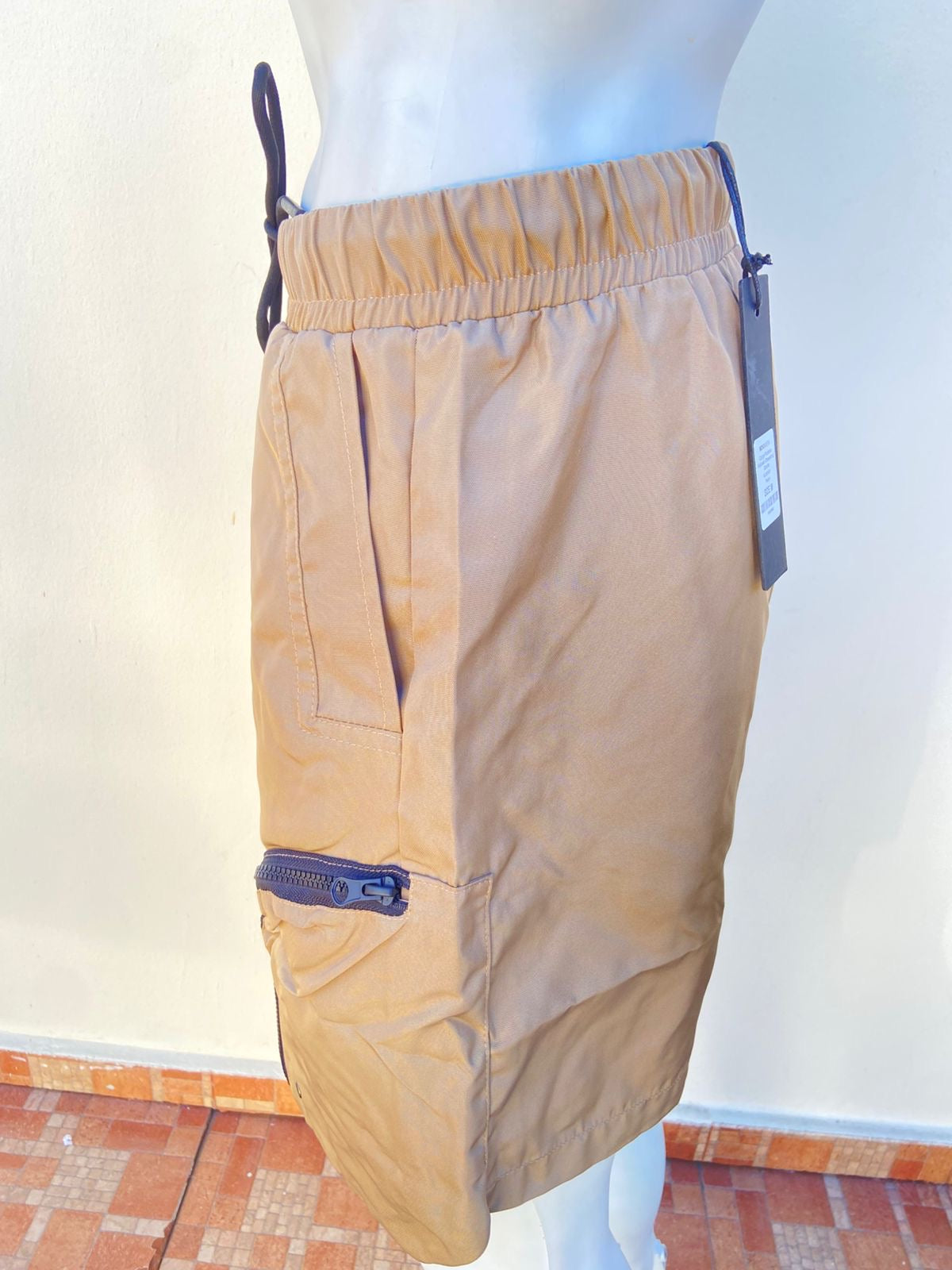 Bermuda, color marrón ( taupe ), con bolsillos y zippers en color negro, estilo cargo.