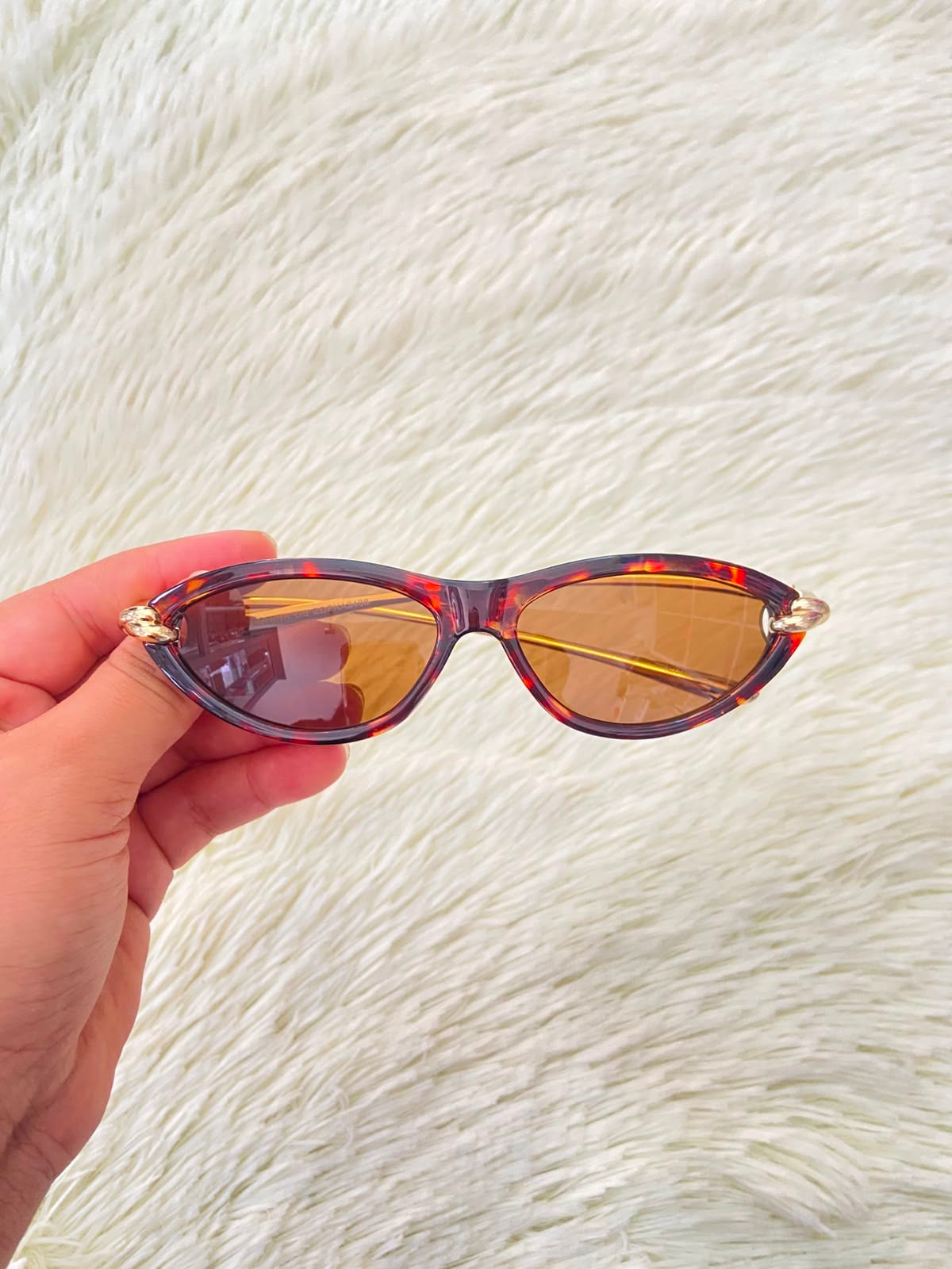 Lentes, montura con estampado de animal print, micas marrones y patillas doradas.