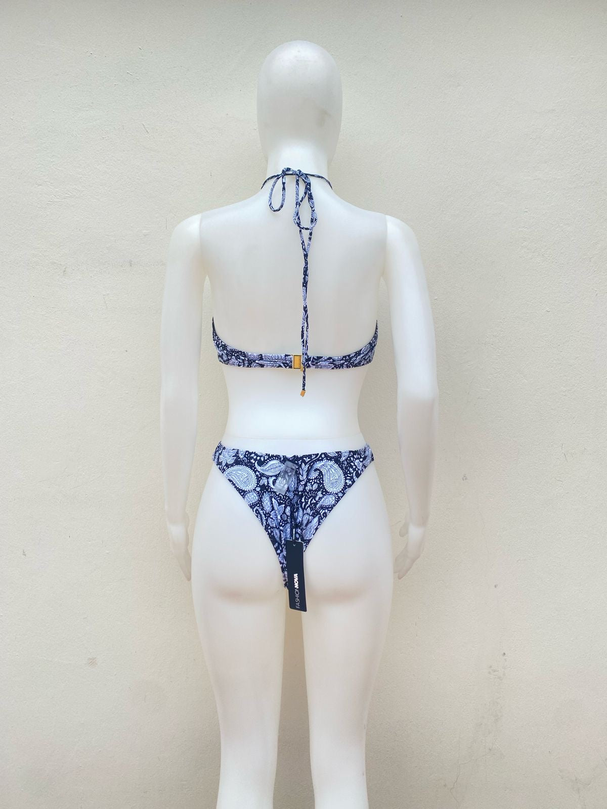 Biquini, de una pieza negro y blanco con estampado de flores y lazo cruzado en la parte superior.