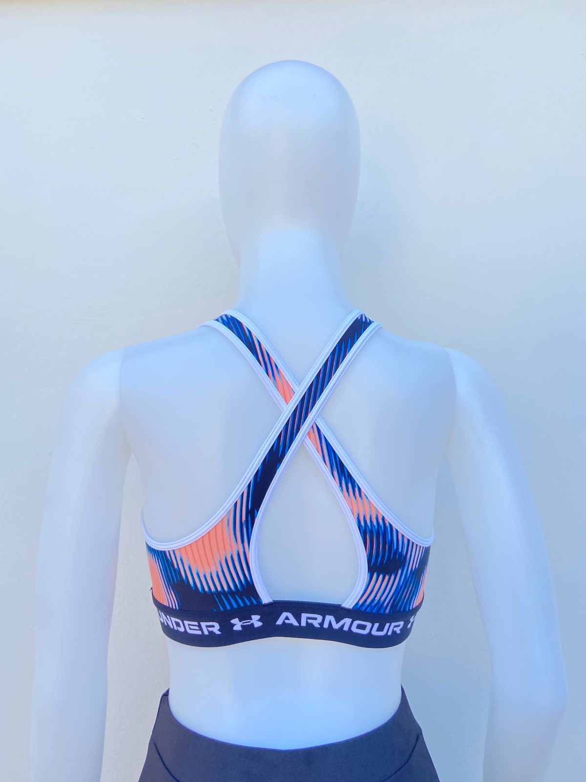 Top UNDER ARMOUR original, azul combinado con rosado neón, espalda cruzada, y letras UNDER ARMOUR en el elástico en color blanco.