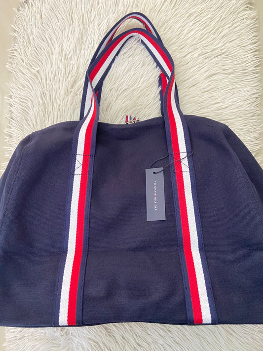 Bulto Tommy Hilfiger Original en color azul marino con logotipo de la marca al frente y lazos en color azul marino rojo y blanco.