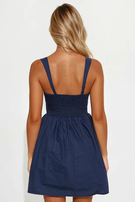 Vestido, algodón orgánico en azul marino ( NAVY) con flor rosada en frente.