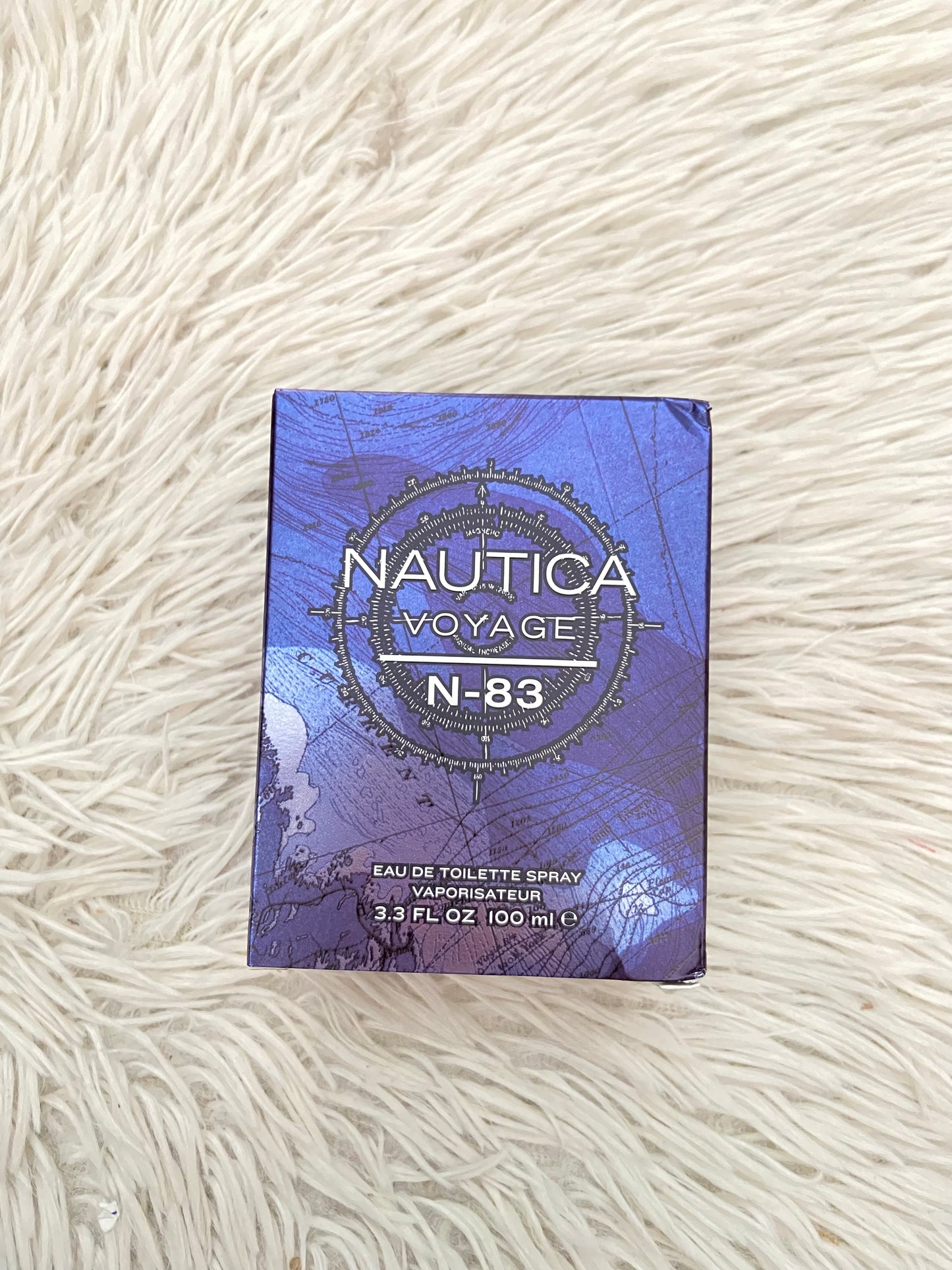 Perfume NAUTICA VOYAGE N- 83 original, azul marino con fondo de una brújula.
