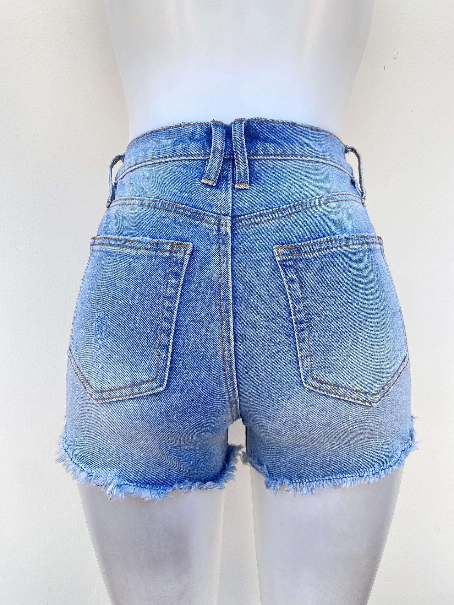 Short Jean, azul claro con rasgados y costura en hilo marrón.