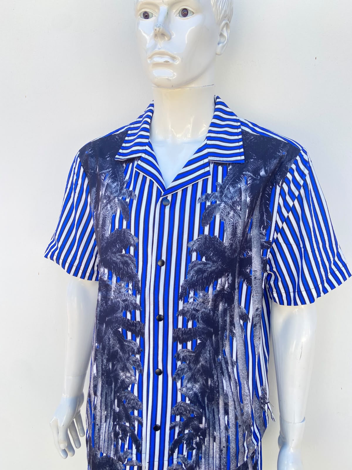 Conjunto, azul con rayas en color blanco y negro y estampado de palmeras, de bañador y camisa.