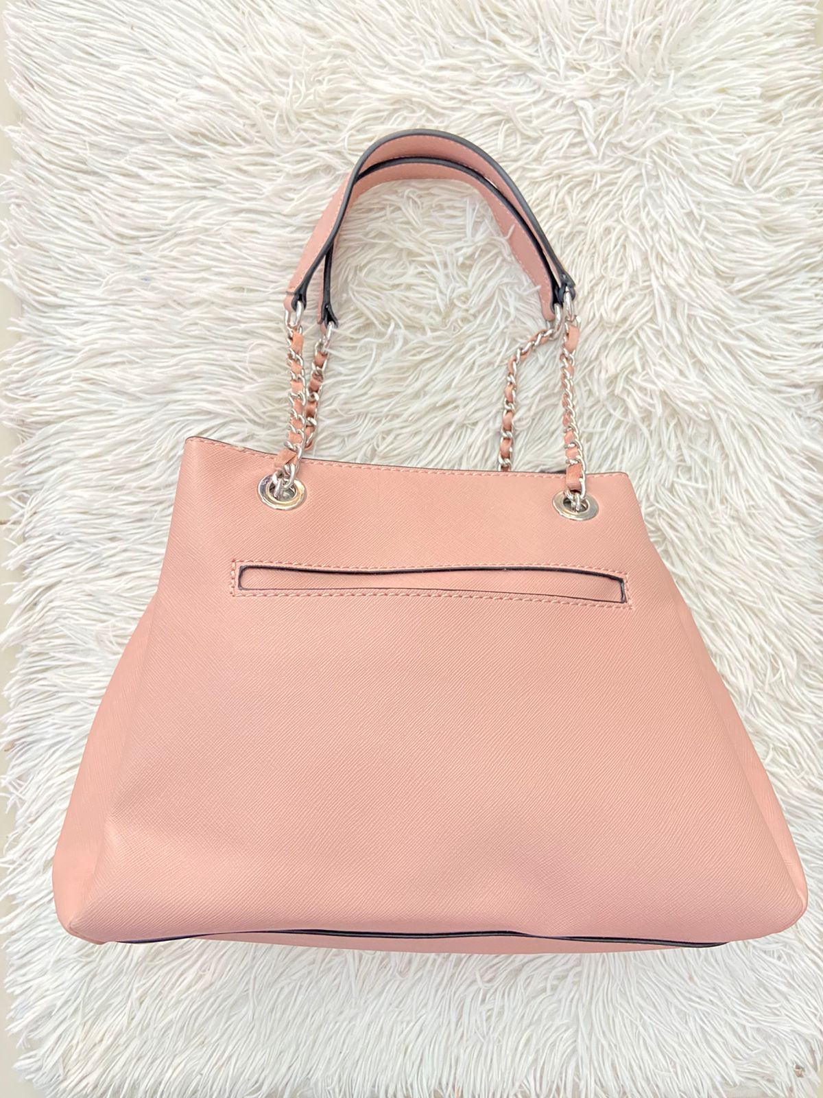 Cartera GUESS Original, color rosado pastel con logo en el centro y asas con cadena plateada.