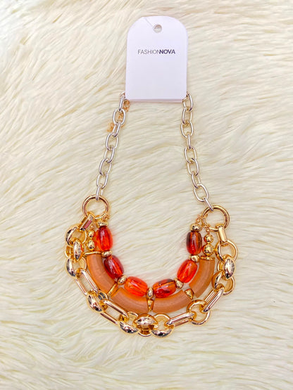 Cadena, dorada con piedras en color rojo y naranja.