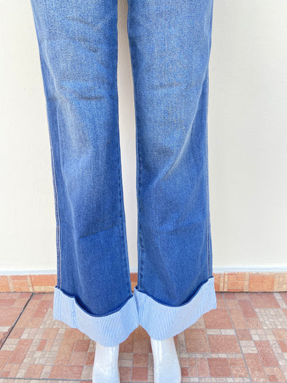 Pantalon Jean azul con tela azul con rayas blancas abajo, alto y con botón en color plateado.
