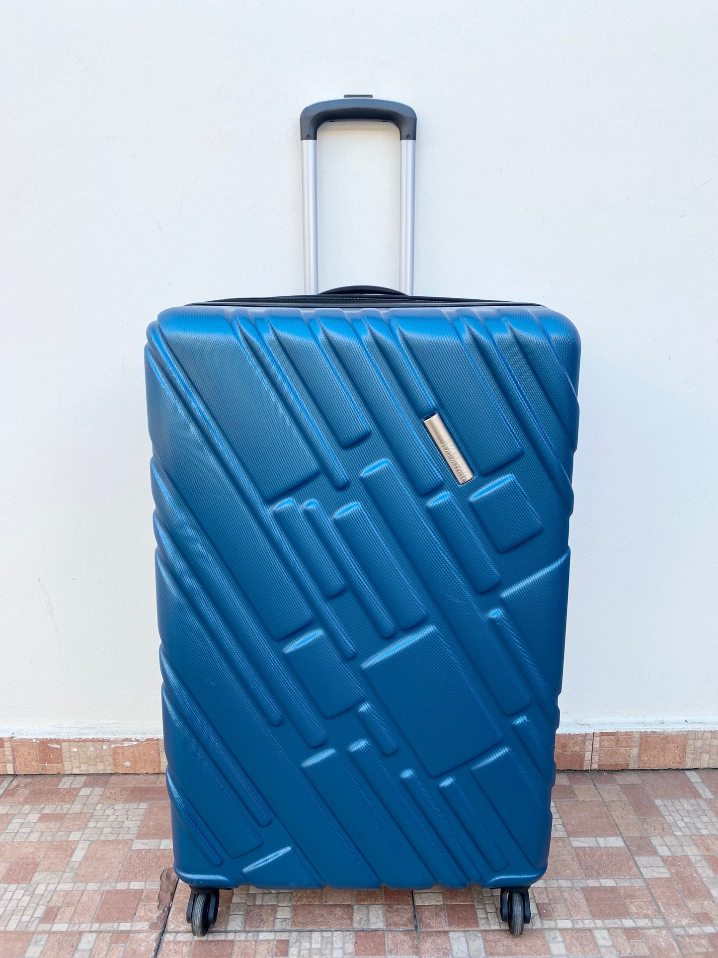 Maleta American Tourister original azul con negro y placa de la marca en frente.