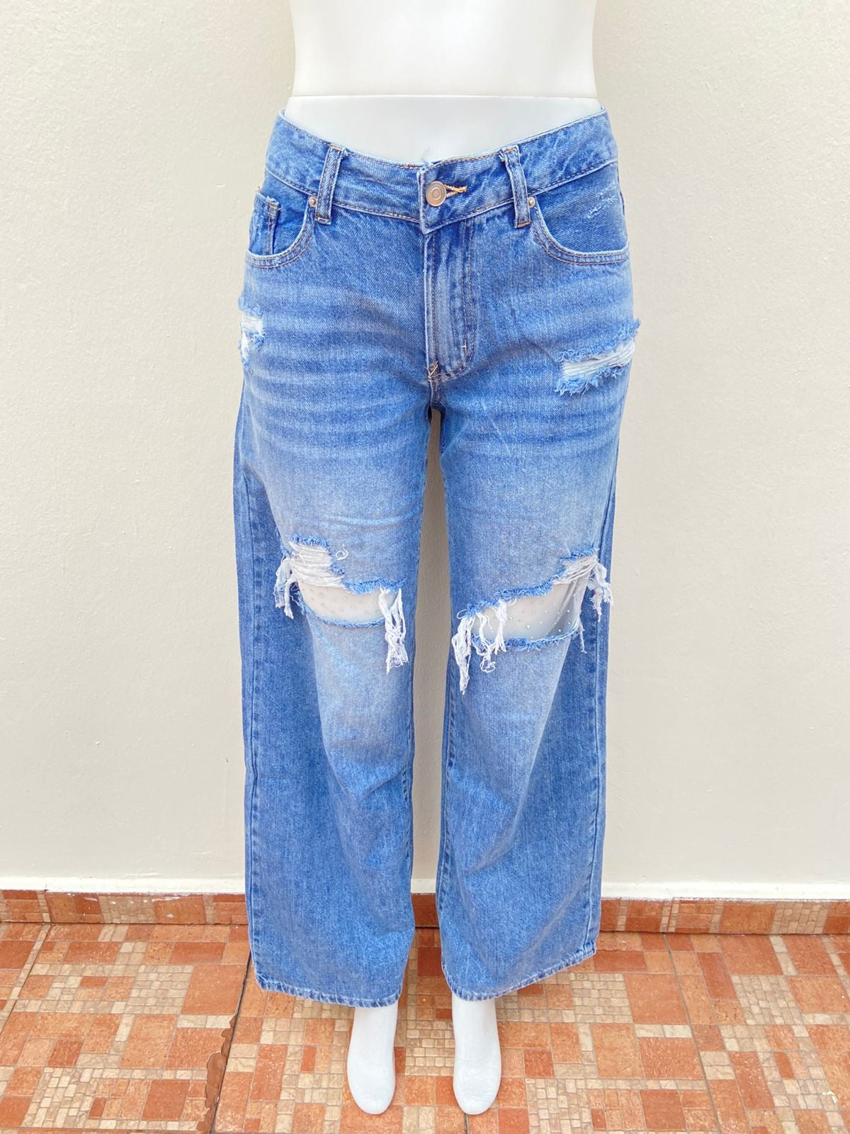 Pantalón Jean, azul con varios rasgados y malla transparente con brillos en los rotos.