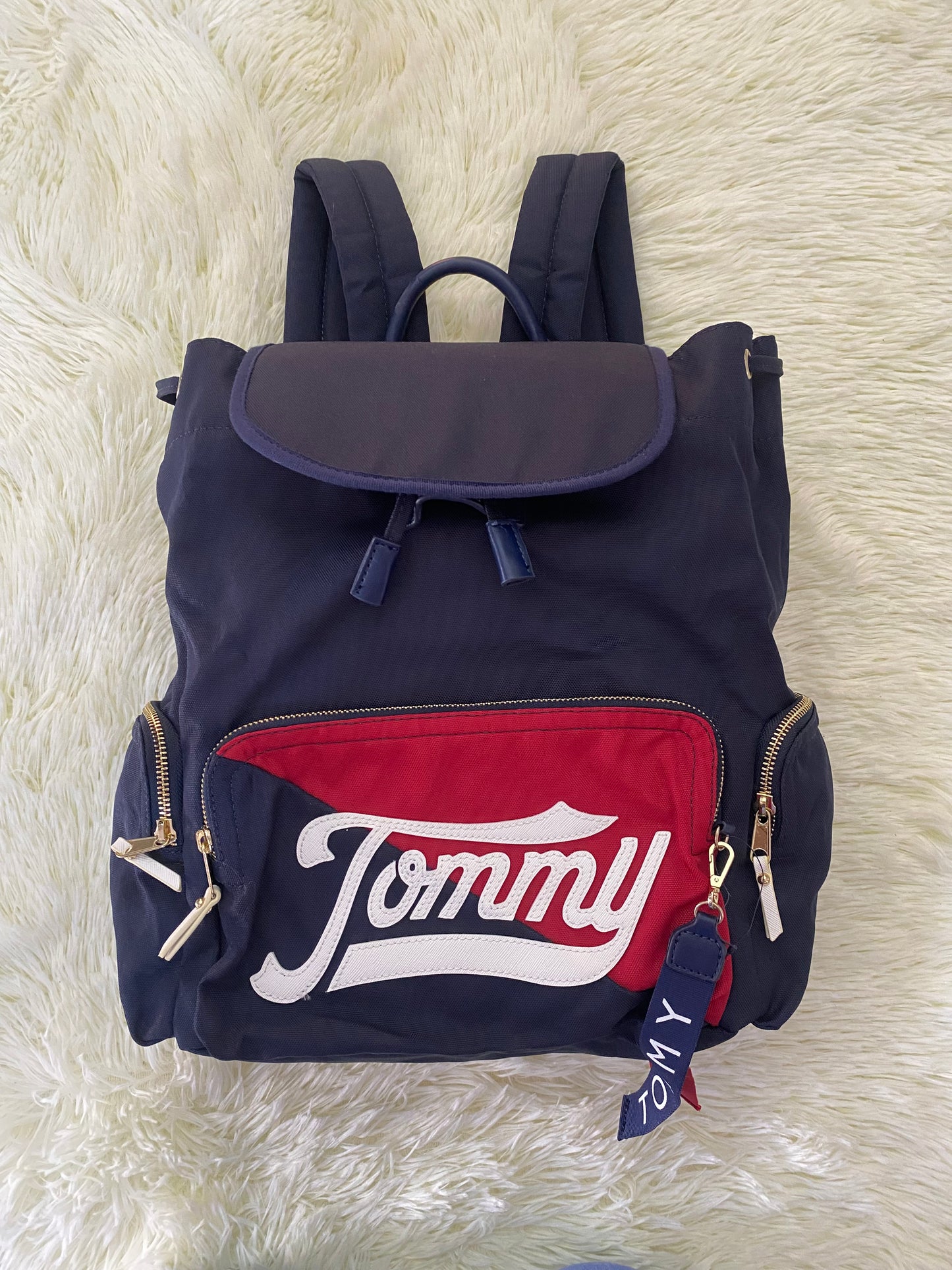 Mochila Tommy Hilfiger original en color azul marino, nombre TOMMY en grande en un bolsillo con el fondo rojo, varios compartimentos, súper espacioso.