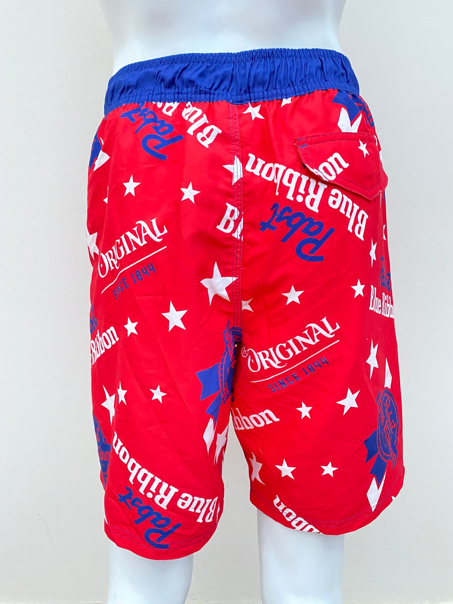 Bañador Baggy Nova Men original, roja con azul con diseños de estrellas en blanco y letras Pabst Blue Ribbon en azul.