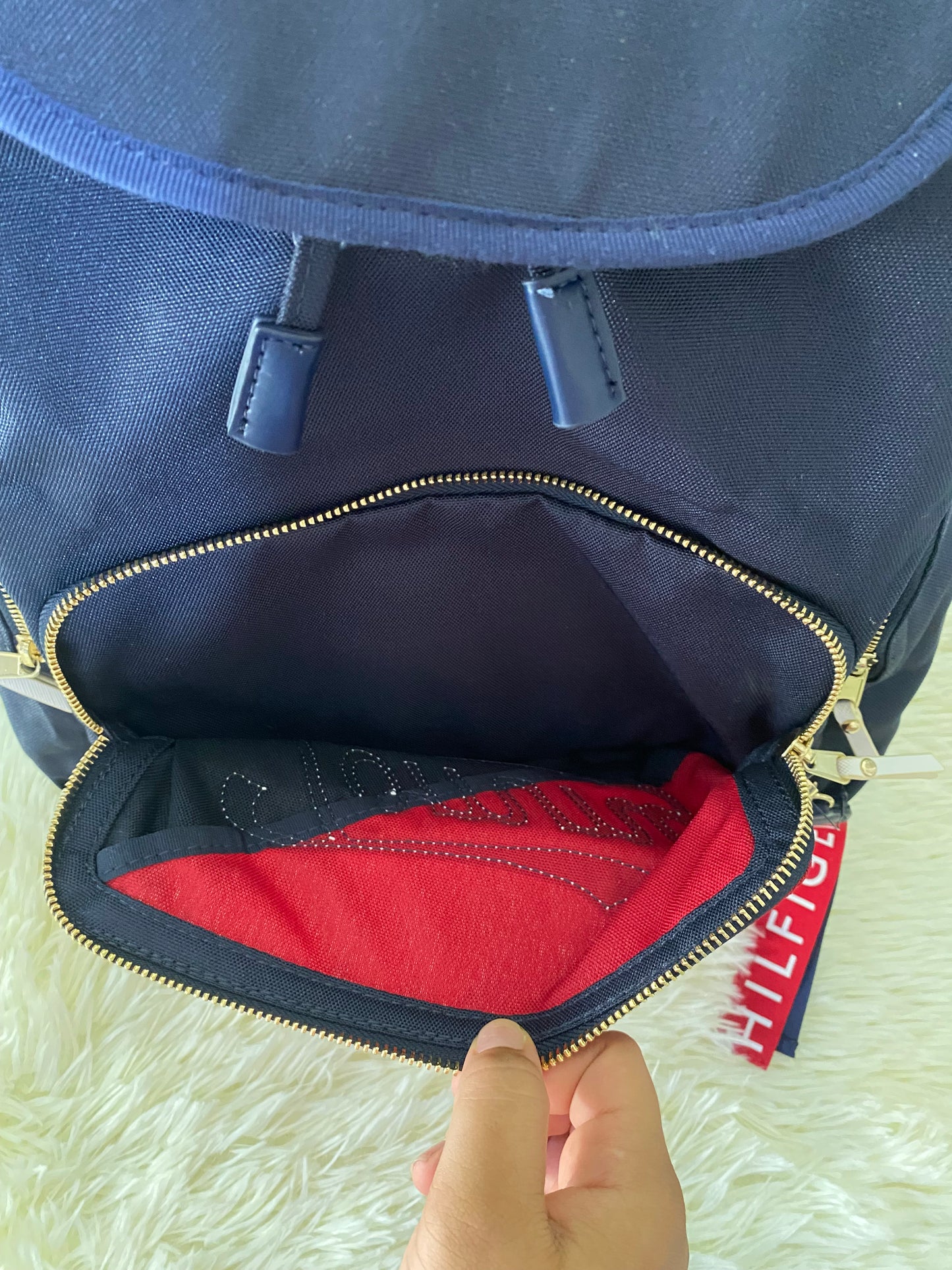Mochila Tommy Hilfiger original en color azul marino, nombre TOMMY en grande en un bolsillo con el fondo rojo, varios compartimentos, súper espacioso.