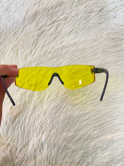 Lentes, sin montura con micas en color amarillo y patillas negras.