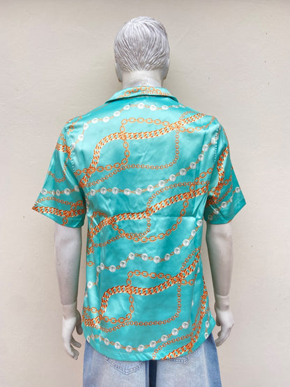 Camisa azul turquesa, con estampado de cadenas y perlas.