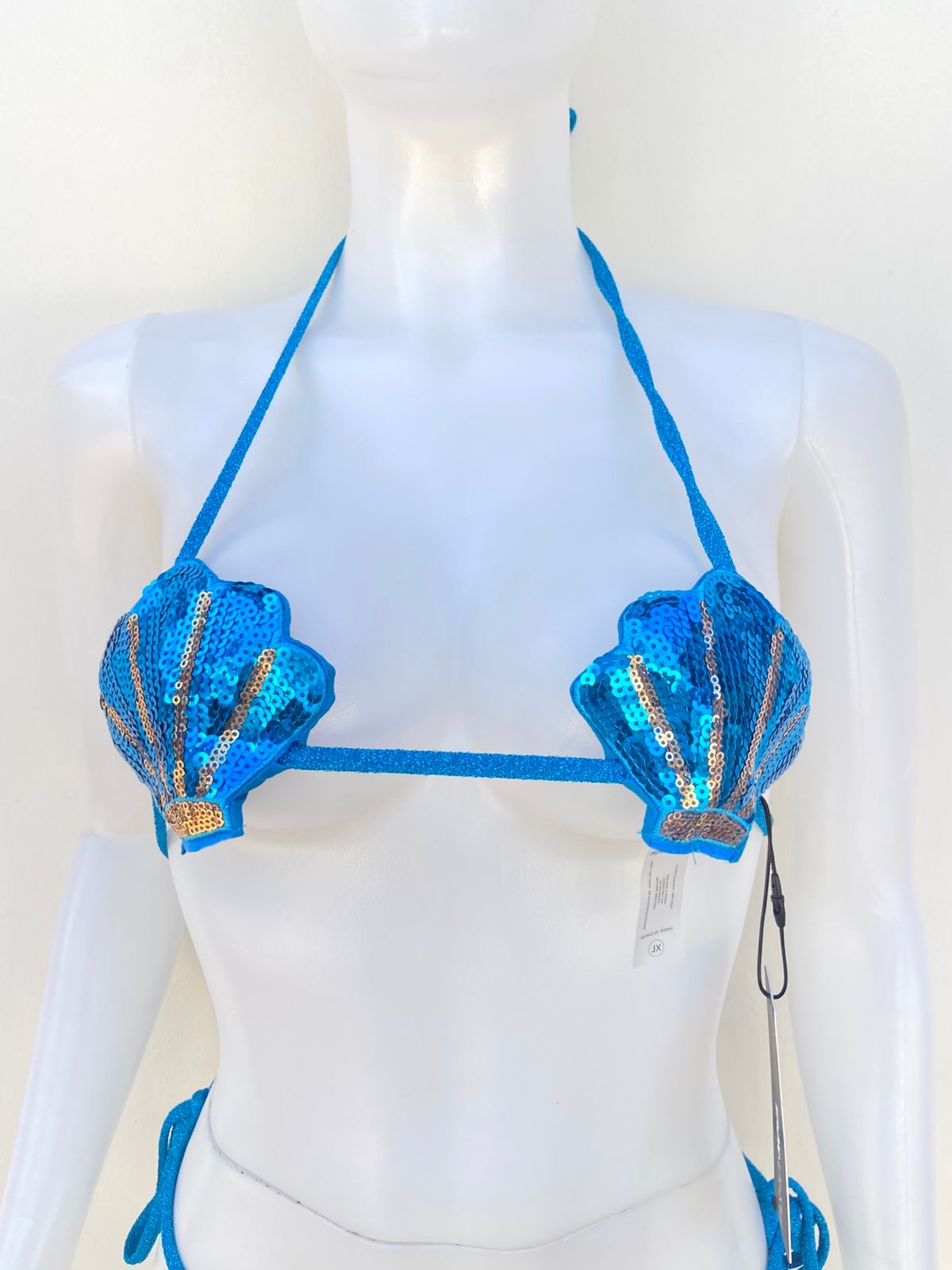 Biquini de dos piezas en color azul turquesa con tela brillante, brasier en forma de concha marina con detalles dorados y lazos ajustables.