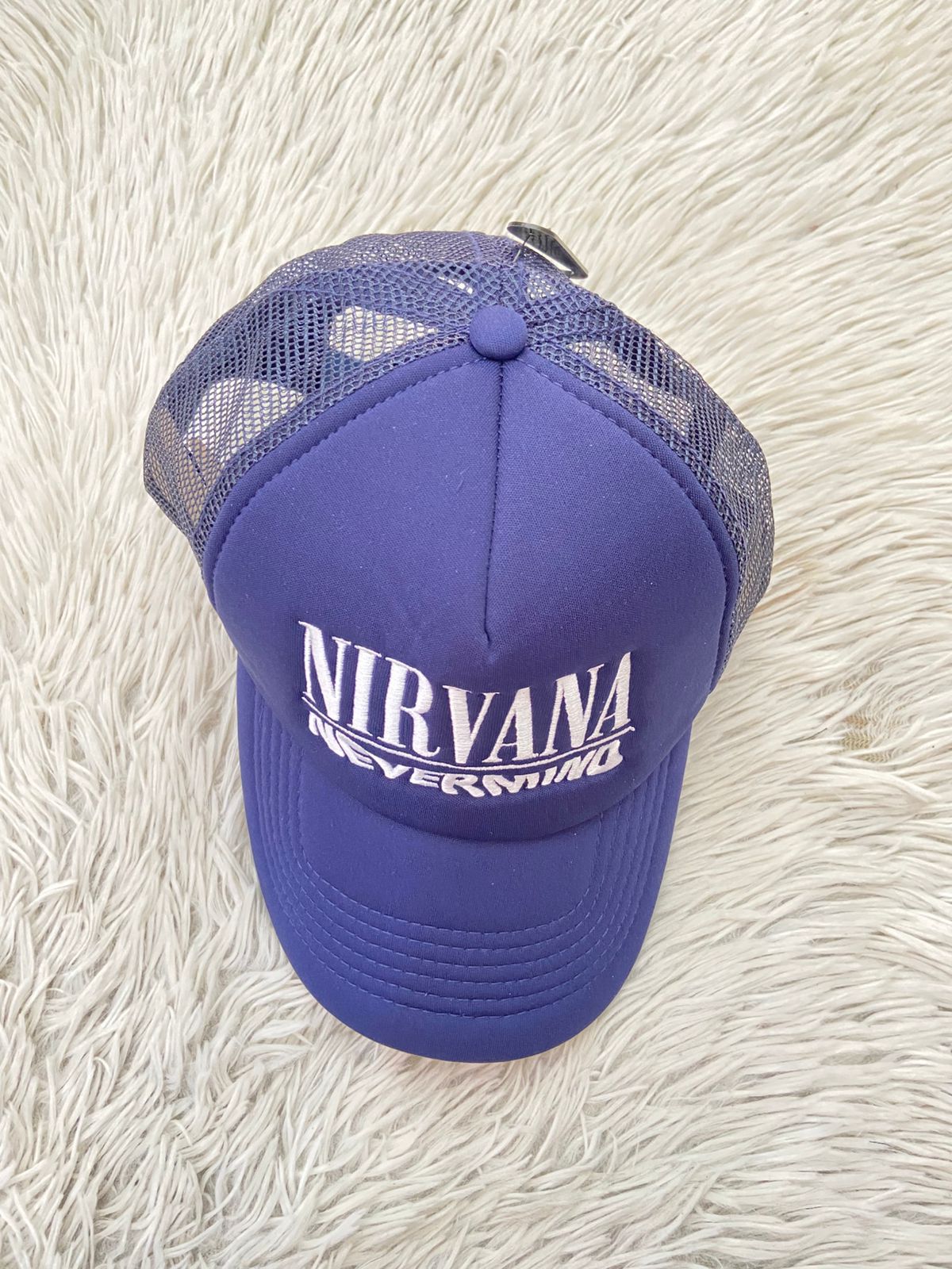 Gorra, azul marino con malla en la parte trasera y letras NIRVANA NEVER MIND en blanco.