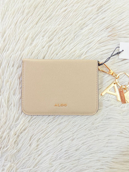 Monedero/ Cartera ALDO Original en color crema con placa de la marca al frente en color dorado y llavero adicional.