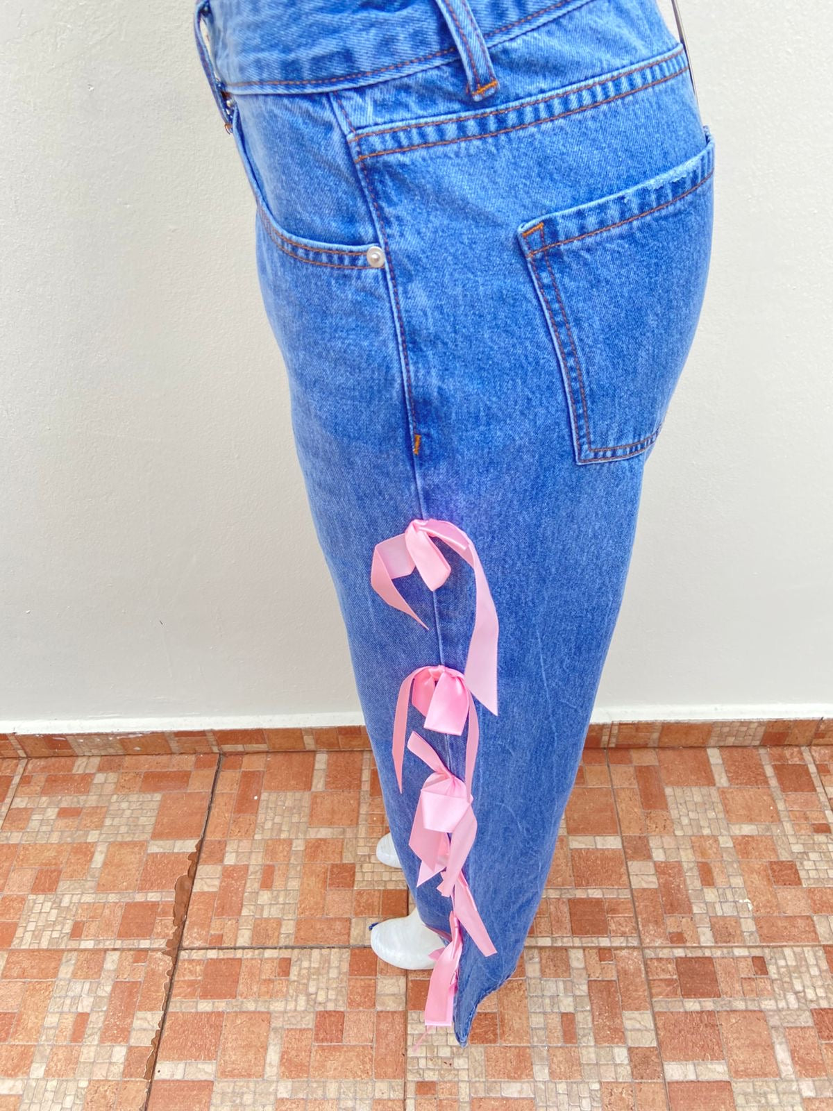 Pantalón Jean, azul liso con lazos en color rosado en los lados.