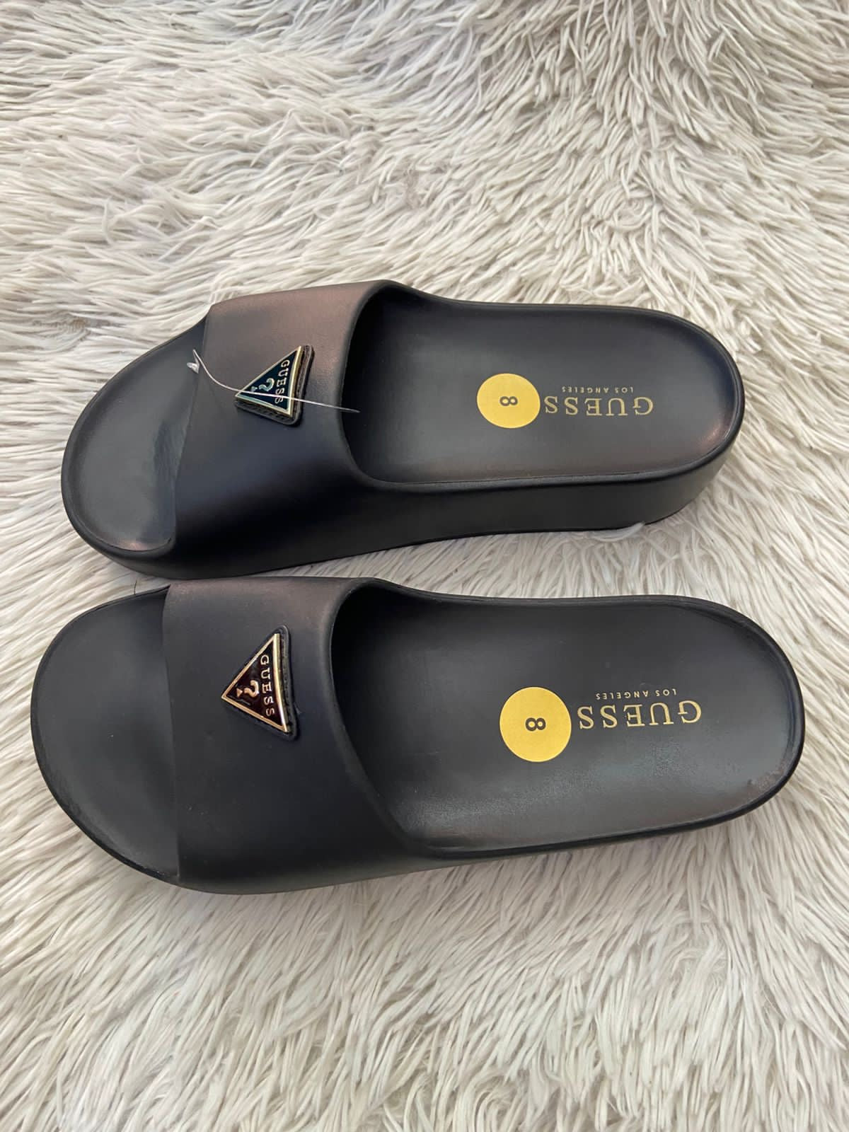 Sandalias GUESS original, negra con plataformas y placa GUESS en frente en color dorado y negro.