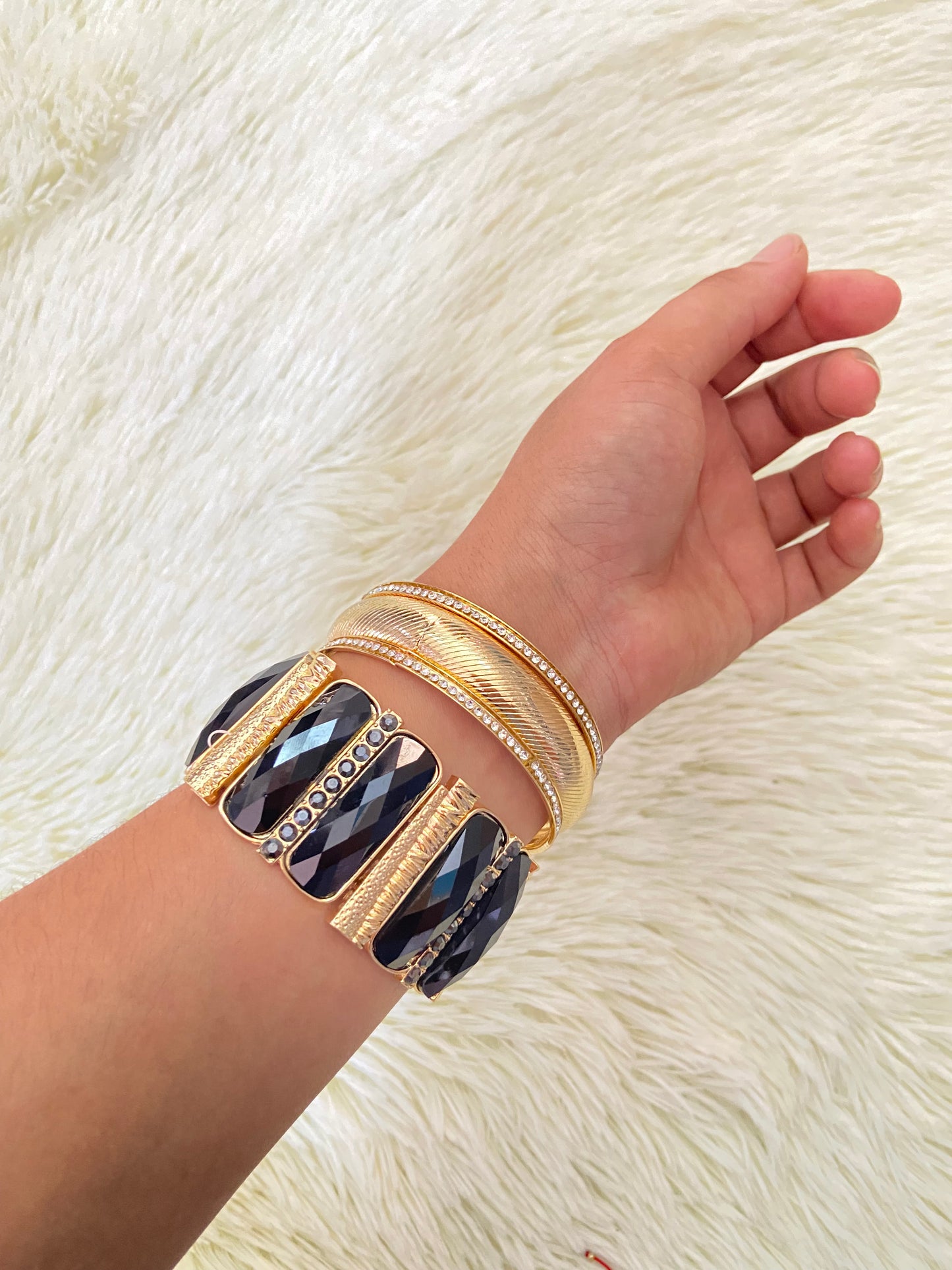 Set de pulseras una en color dorado con detalles plateados y otra con Piedras grandes negras y doradas.