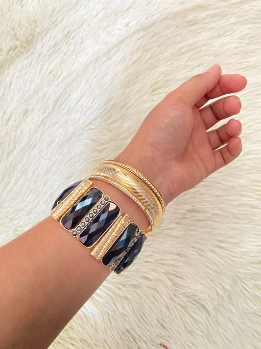 Set de pulseras una en color dorado con detalles plateados y otra con Piedras grandes negras y doradas.