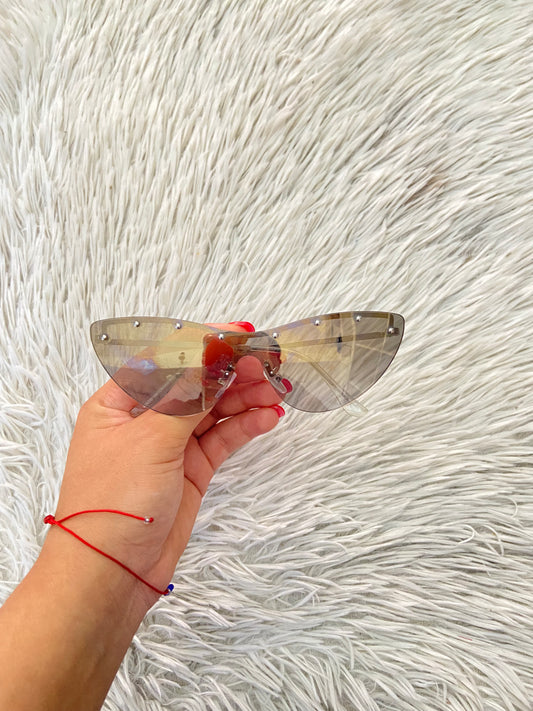 Lentes diseñados con protección UV 100-400 para proteger tu visión. Micas en dorado/beige y detalle de piedras plateado arriba.