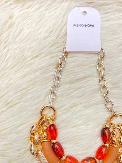 Cadena, dorada con piedras en color rojo y naranja.