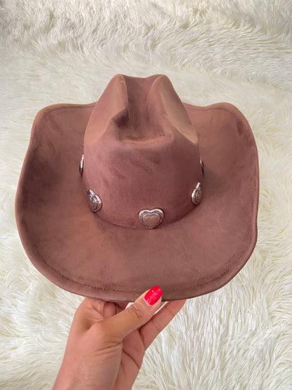 Sombrero, marron oscuro con placas de corazón al rededor en plateado, estilo vaquero.