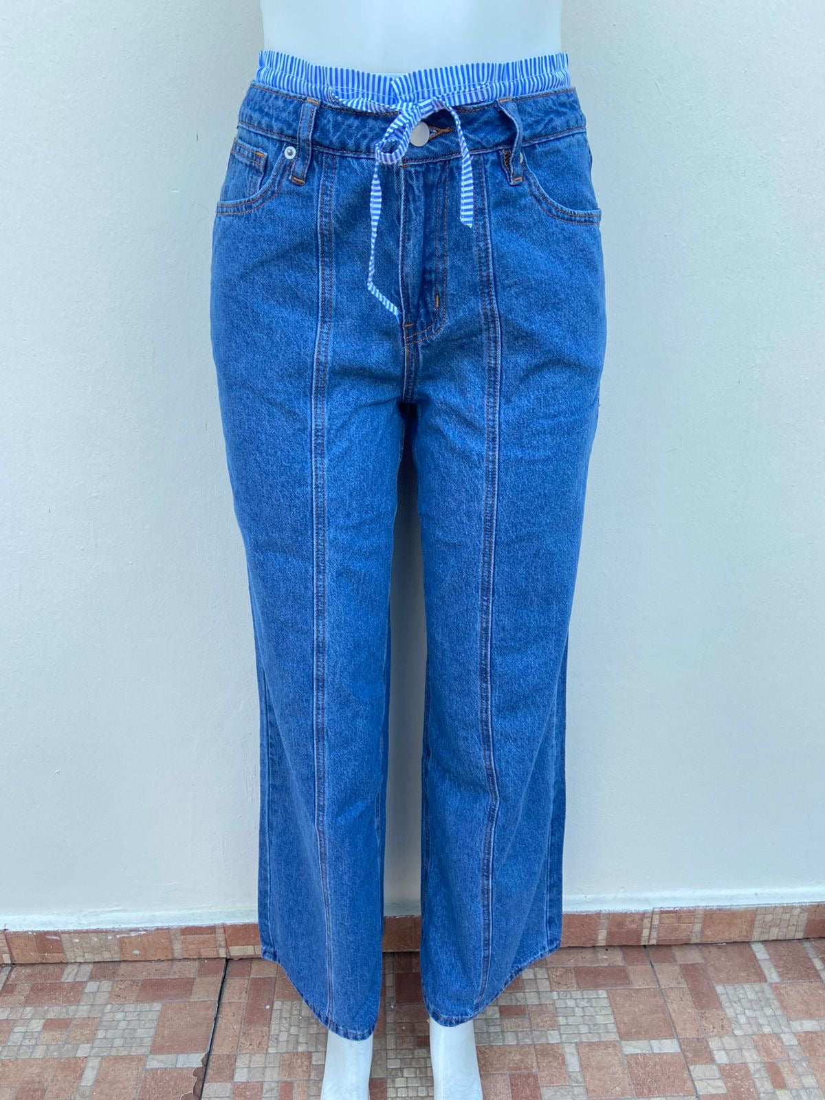 Pantalon jean azul liso con tela con lazos ajustable color azul arriba de la pretina, ancho.