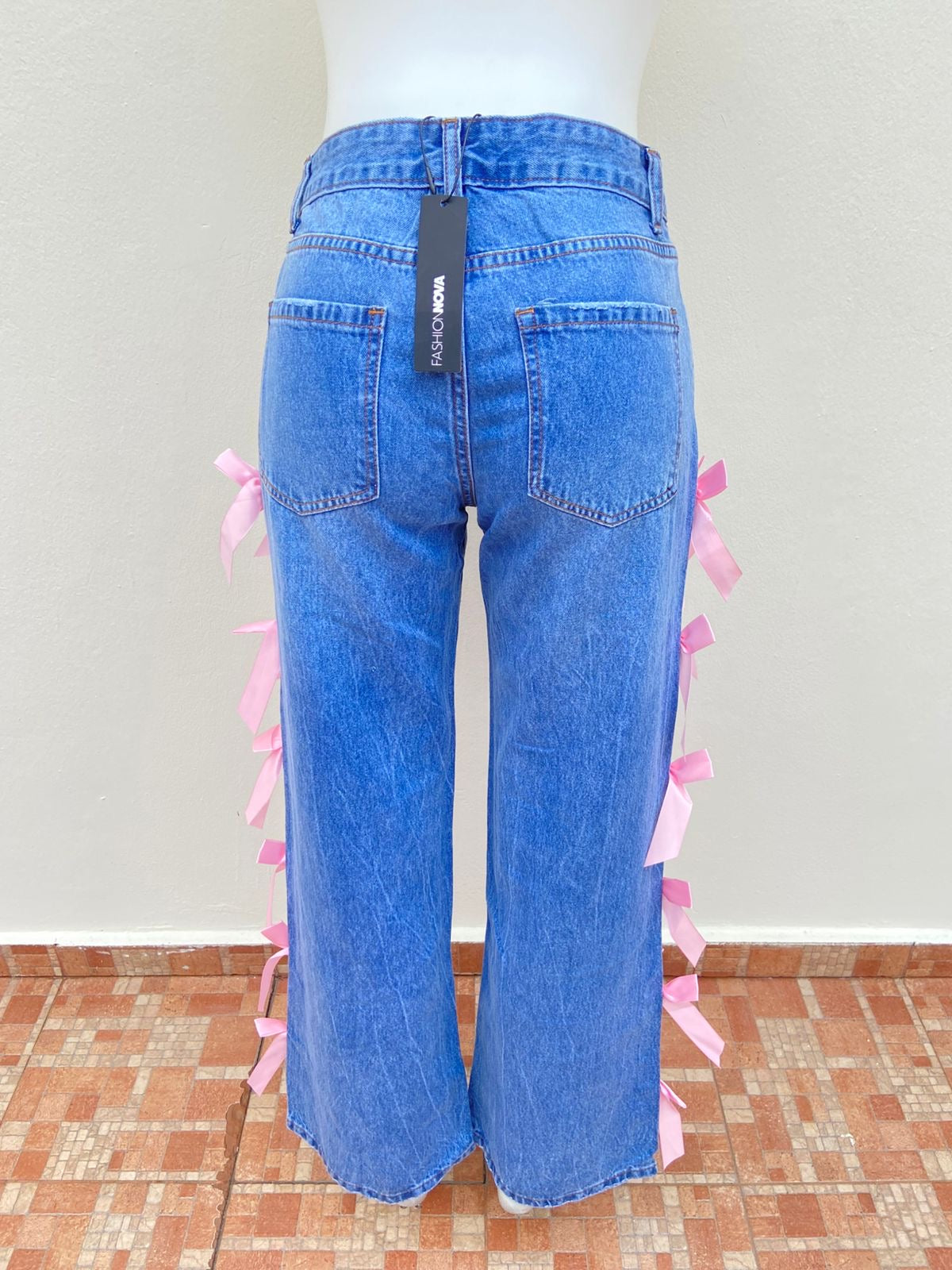 Pantalón Jean, azul liso con lazos en color rosado en los lados.