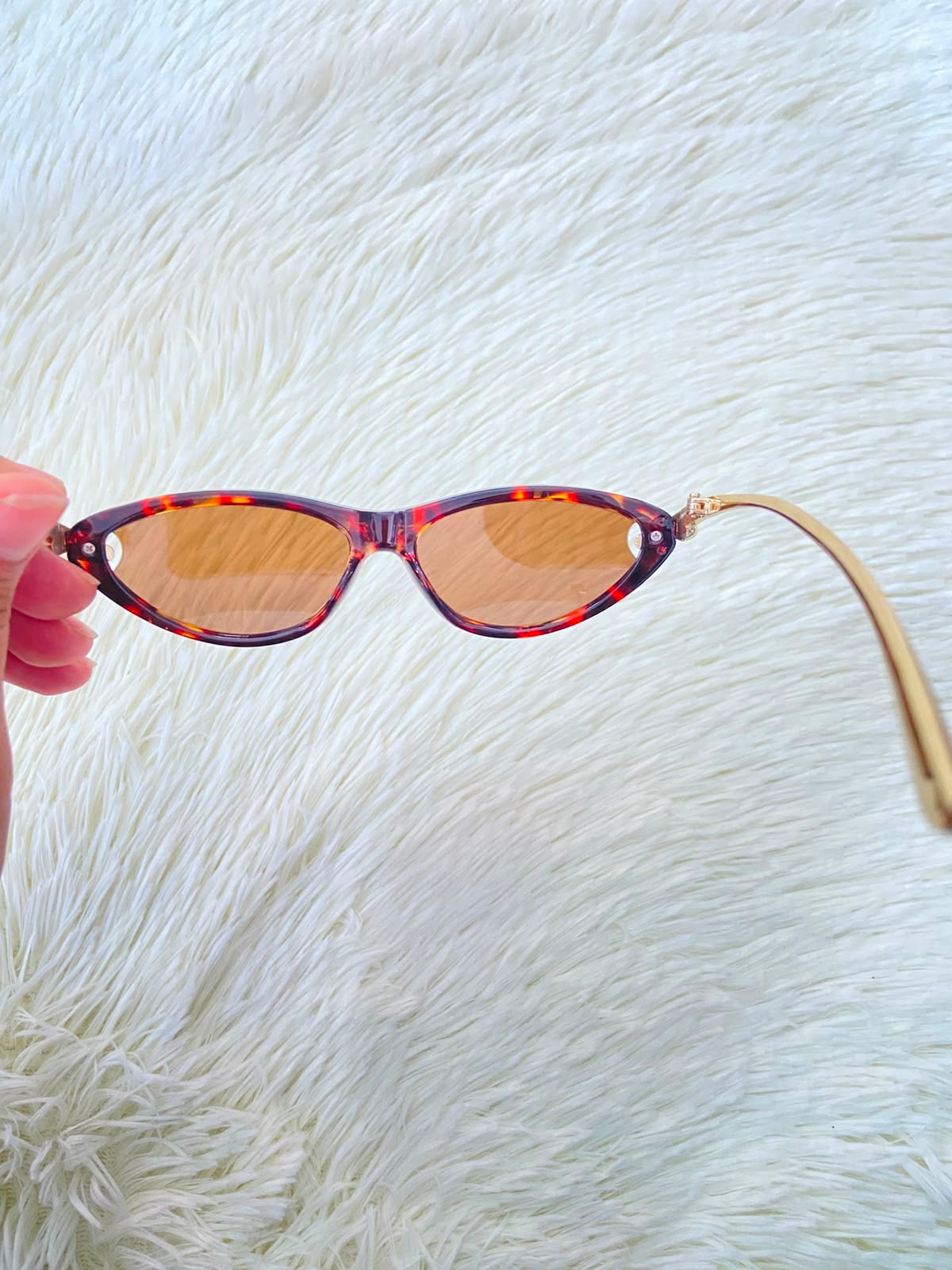 Lentes, montura con estampado de animal print, micas marrones y patillas doradas.