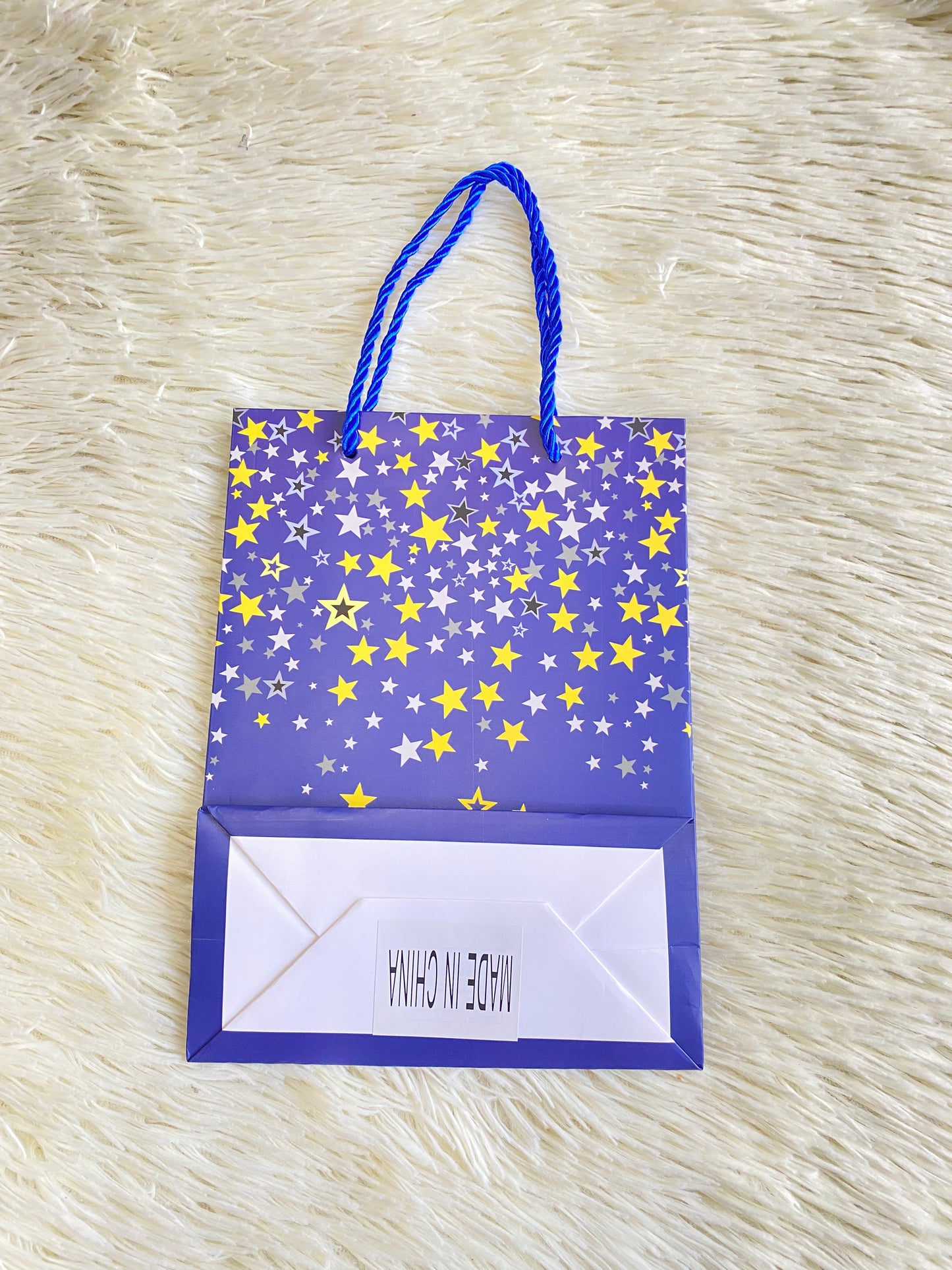 Shopping azul marino con estrellas doradas y letras felicidades debajo. PEQUEÑO