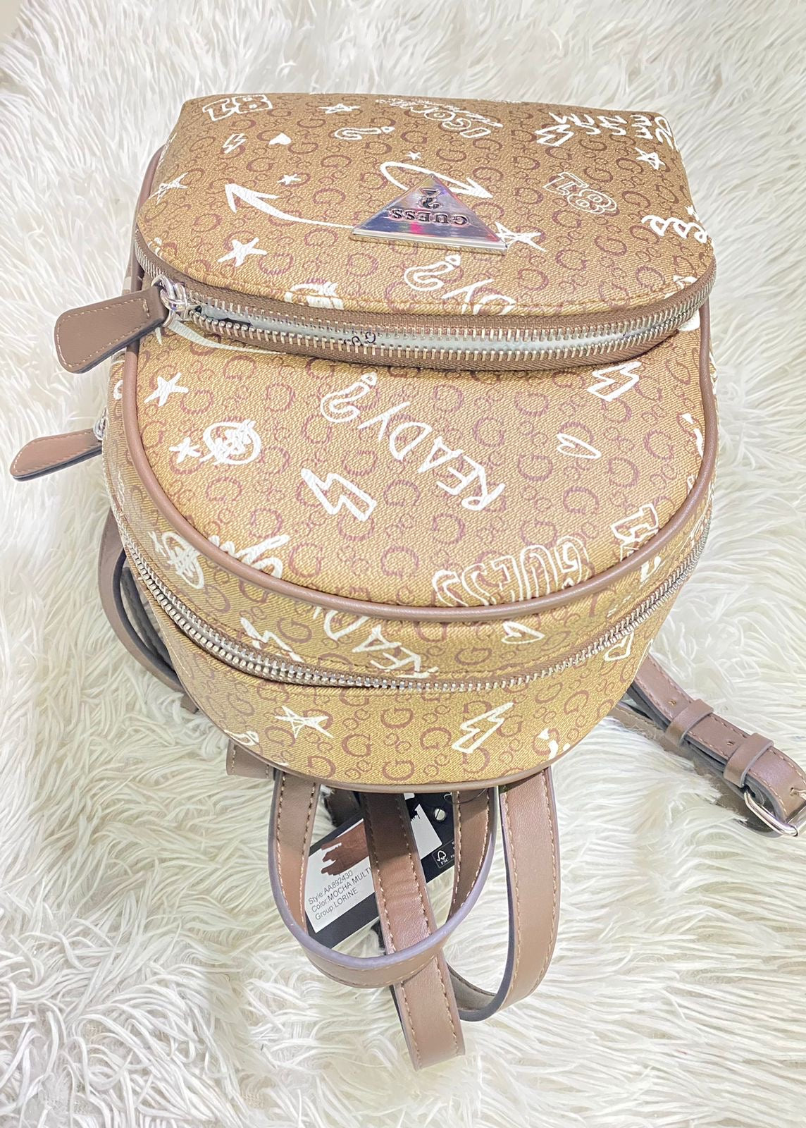 Mochila Guess original marrón con estampado de la marca en blanco y placa Guess en plateado.