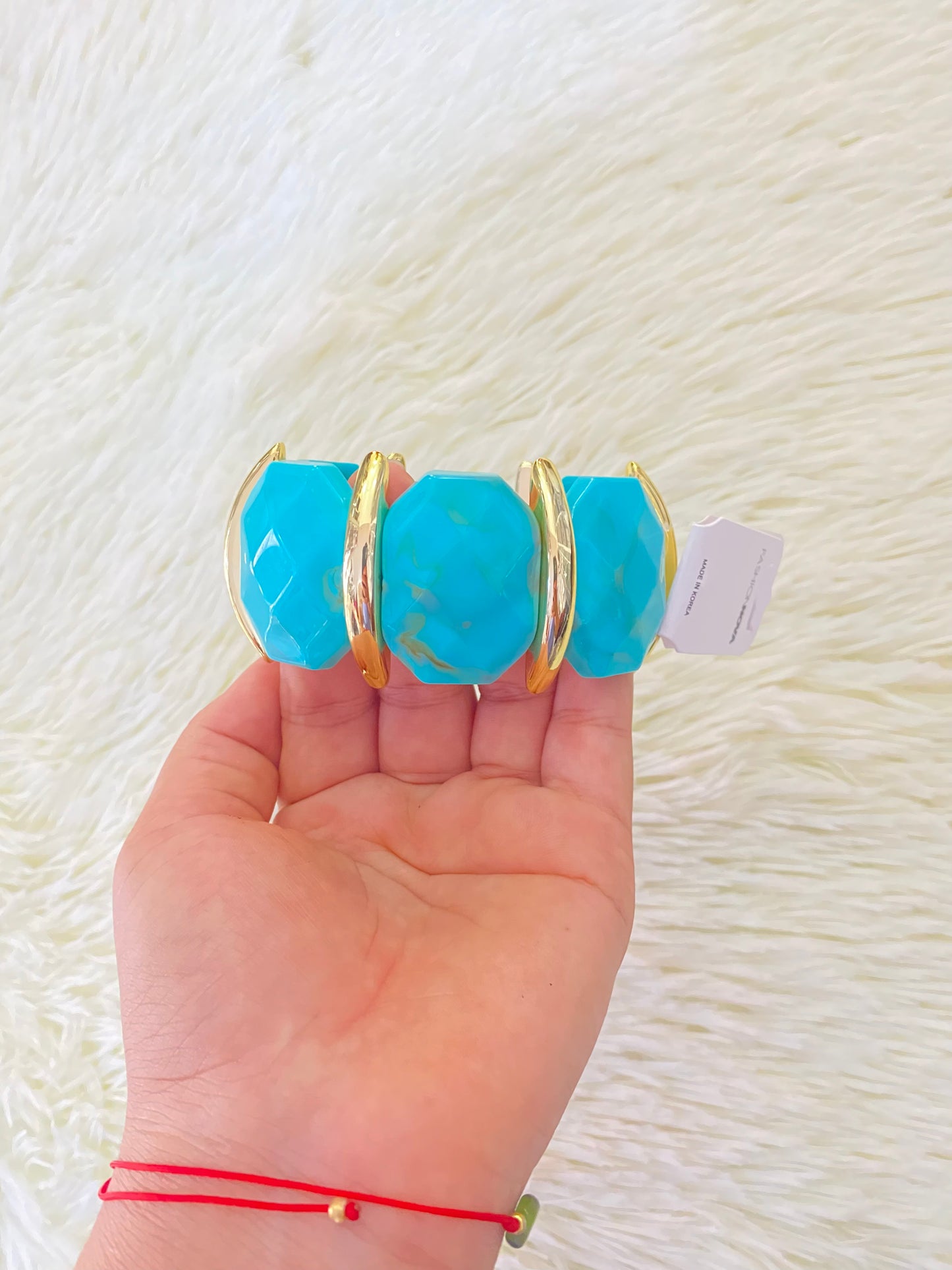 Pulsera en color azul turquesa con detalles dorados.