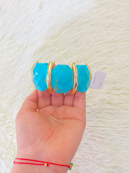 Pulsera en color azul turquesa con detalles dorados.