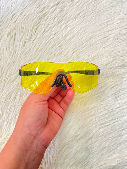 Lentes, sin montura con micas en color amarillo y patillas negras.