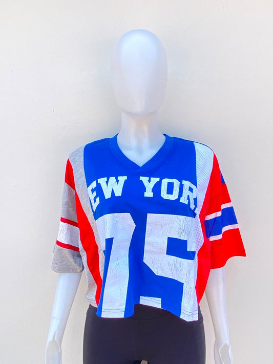 Crop-top en color azul con mangas en color rojo, gris y blanco. con letra New York y numero 75 al frente.