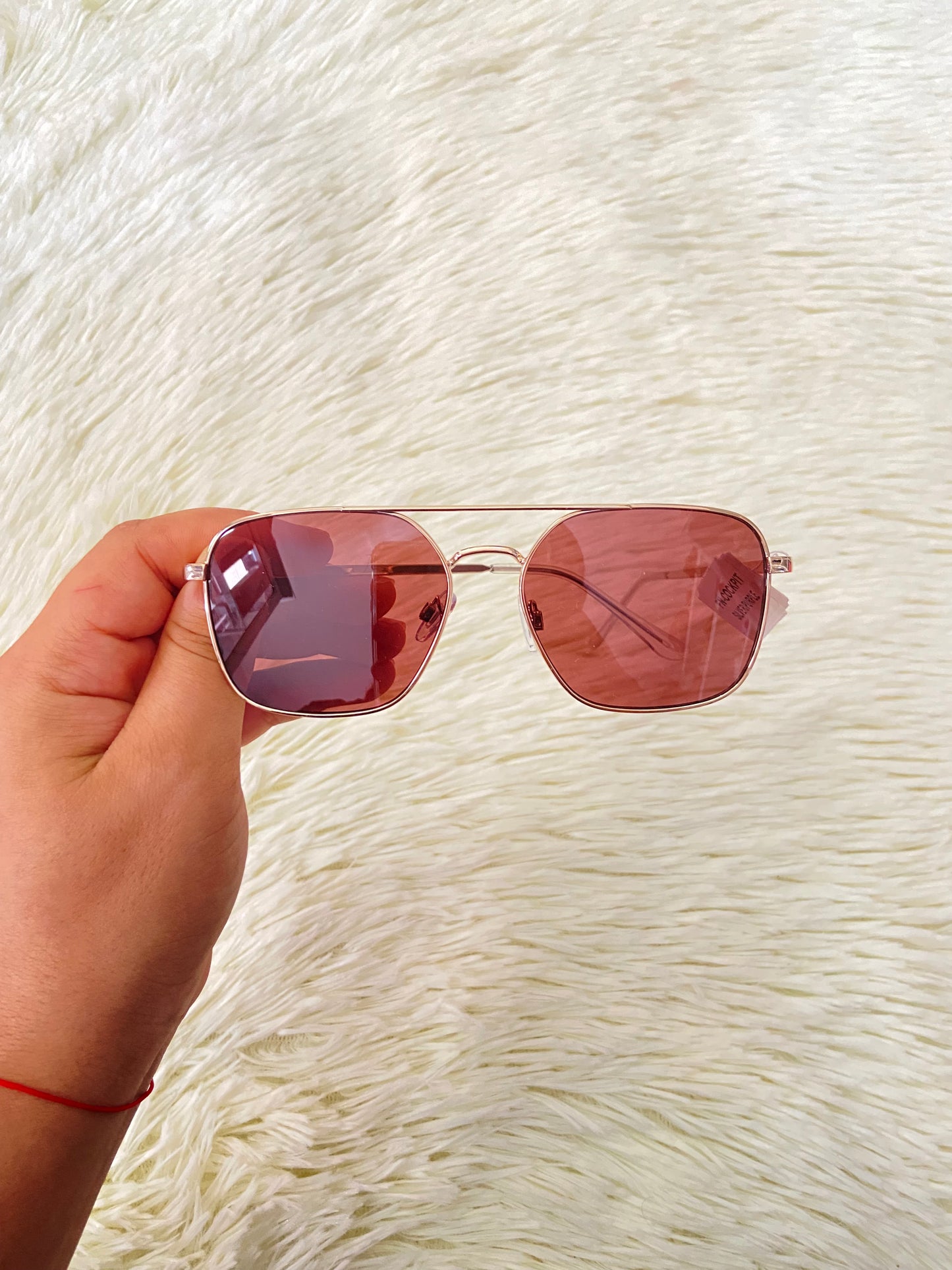 Lentes con montura metálica delgada con tono dorado/rosado, micas rosadas.