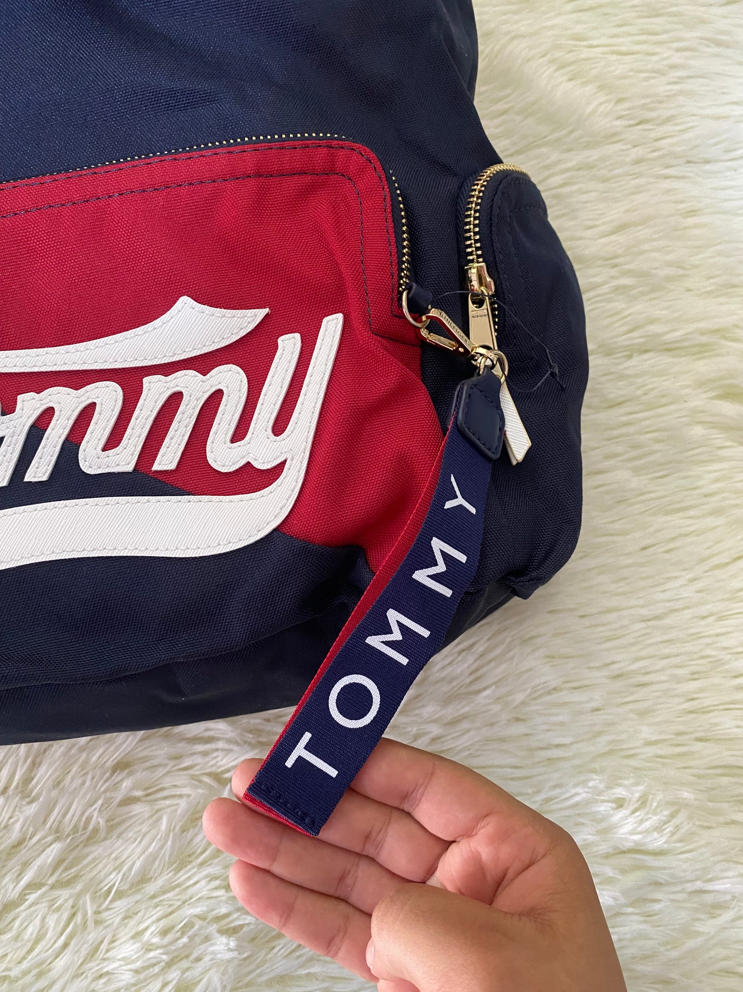 Mochila Tommy Hilfiger original en color azul marino, nombre TOMMY en grande en un bolsillo con el fondo rojo, varios compartimentos, súper espacioso.