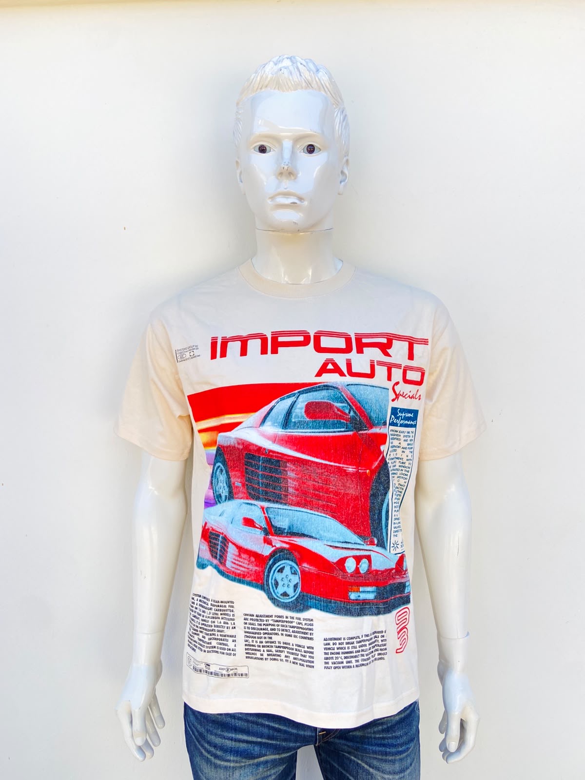T-shirt en color beige/crema con imagen al frente de carro rojo y letra grande en color rojo, IMPORT AUTO y más en color azul pequeñas, 100% algodón.
