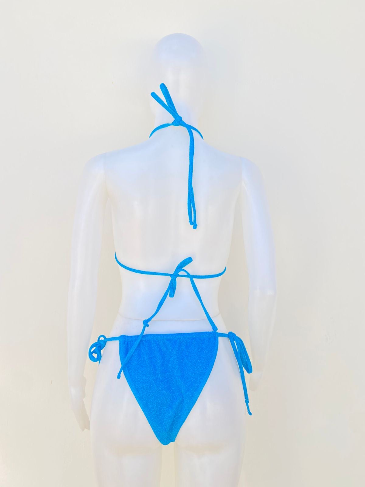 Biquini de dos piezas en color azul turquesa con tela brillante, brasier en forma de concha marina con detalles dorados y lazos ajustables.