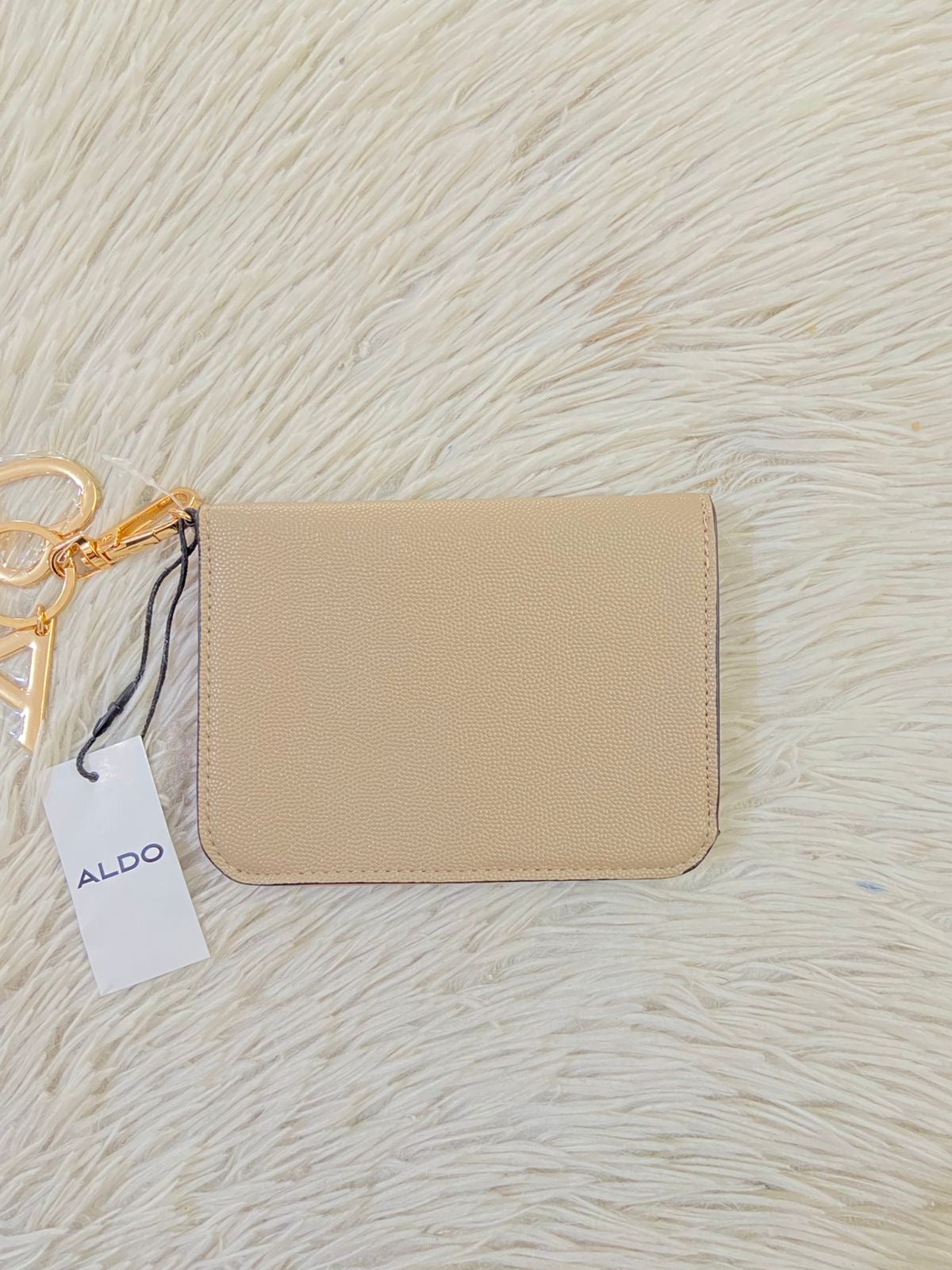 Monedero/ Cartera ALDO Original en color crema con placa de la marca al frente en color dorado y llavero adicional.