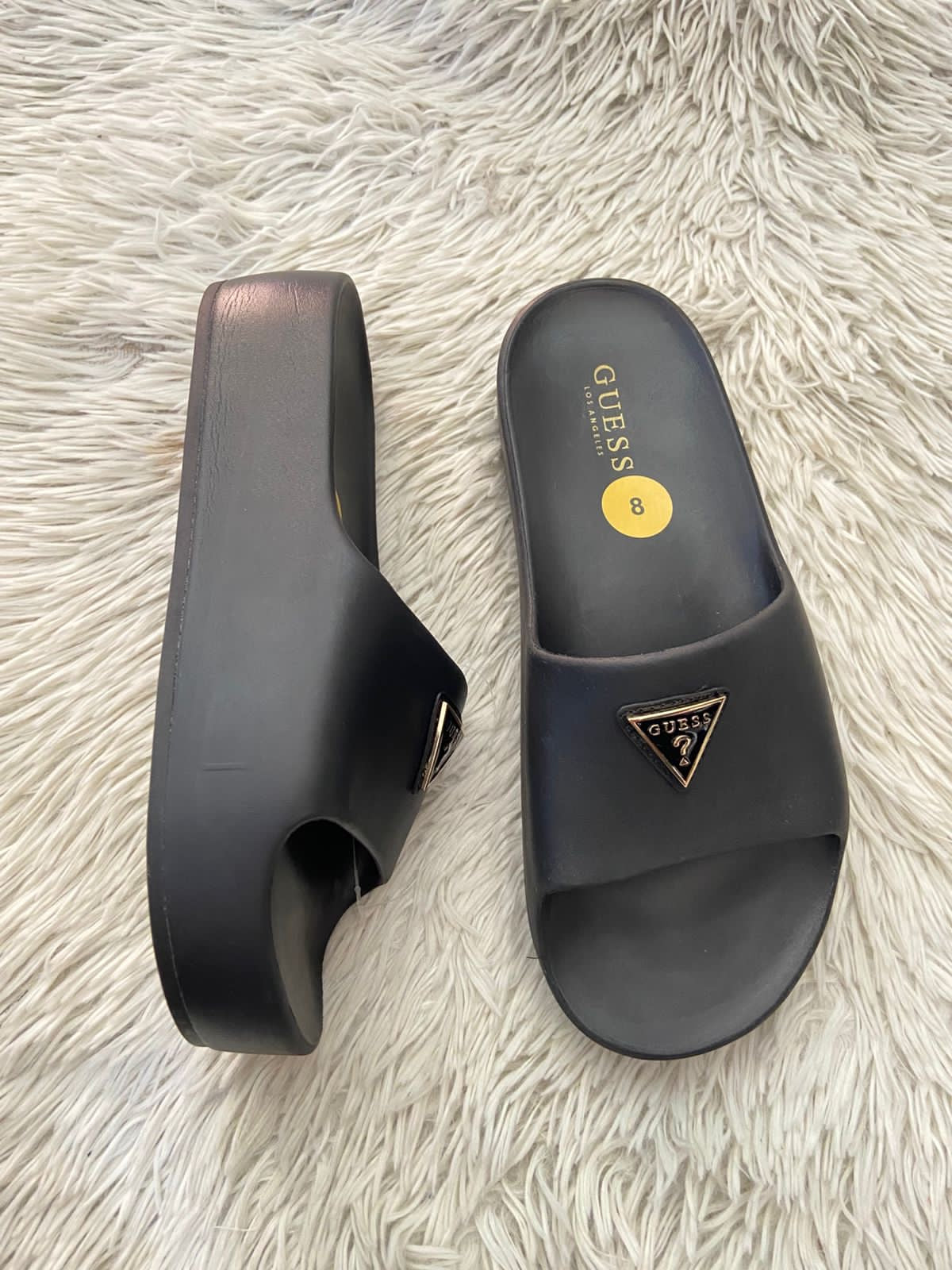 Sandalias GUESS original, negra con plataformas y placa GUESS en frente en color dorado y negro.